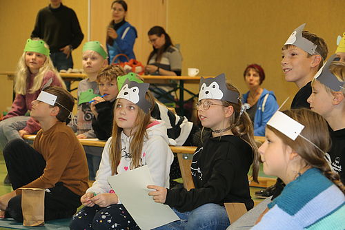 Viele Kinder sind zu sehen, mit Stirnbändern aus Papier auf dem Kopf, die Tiere zeigen