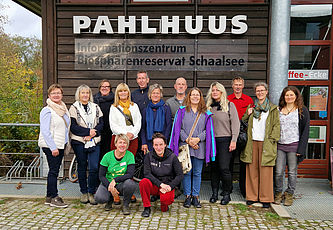 Viele Personen stehen vor einem Gebäude mit der Aufschrift "Pahlhuus".